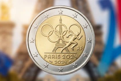 Detailed 2 euro coin for Paris 2024 Olympics, with Eiffel Tower, Olympic rings, athlete, and "PARIS 2024". Blurred background.