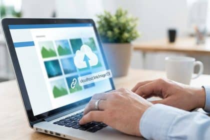 Mains tapant sur un ordinateur portable affichant une interface d'hébergement d'images avec un icône de nuage et un lien d'accès.