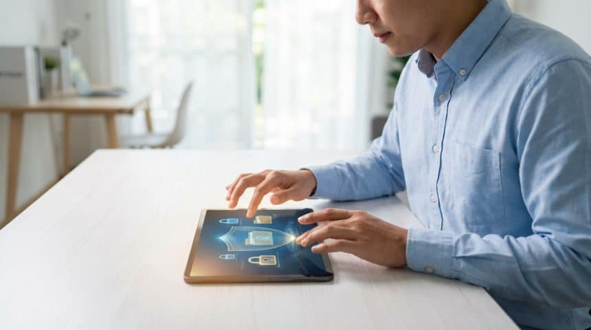 Un homme utilise une tablette affichant des symboles de sécurité pour accéder à ses fiches de paie dématérialisées via Nibelis.