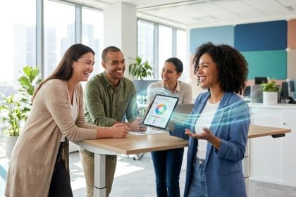 Une équipe souriante partageant des résultats sur une tablette dans un bureau lumineux et moderne.
